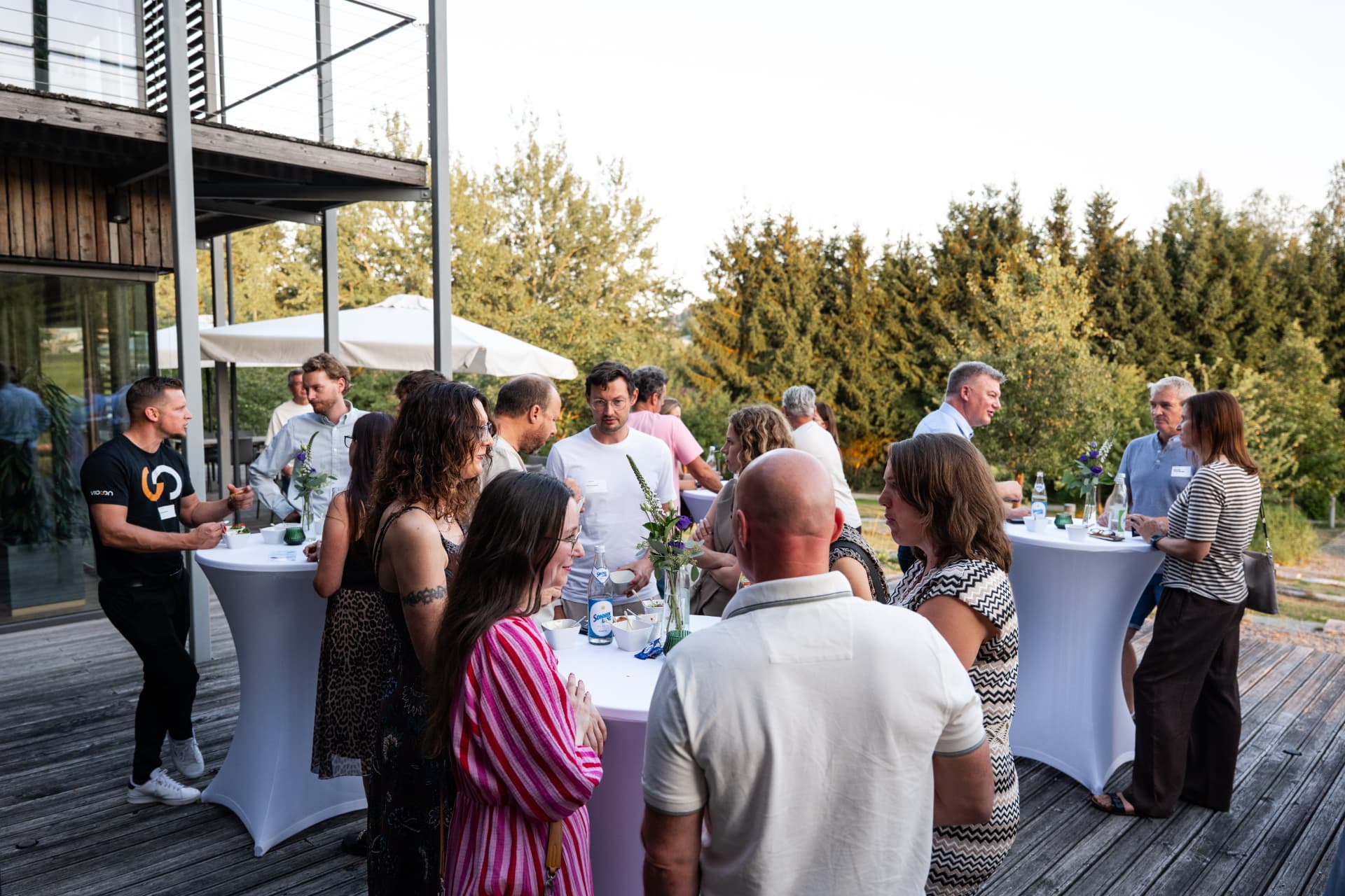 Gäste im Gespräch an Stehtischen auf der Terrasse
